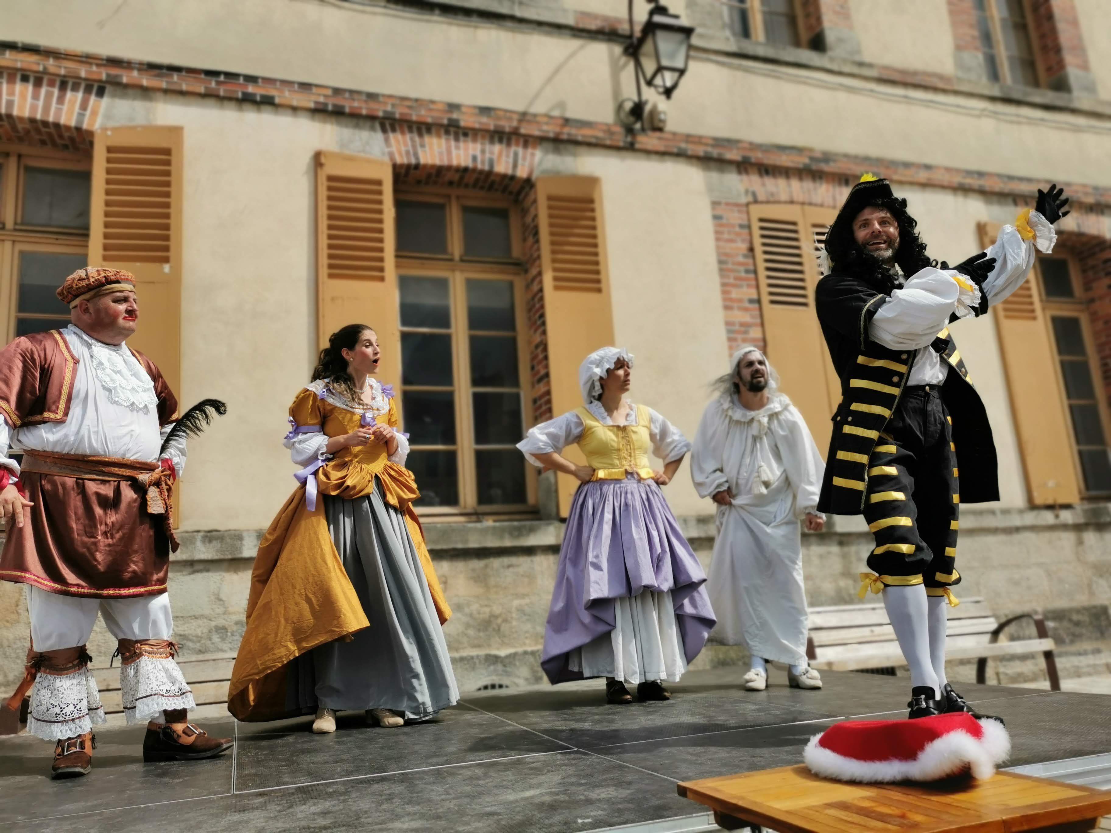 Cinq comédiens jouant une pièce de théâtre.