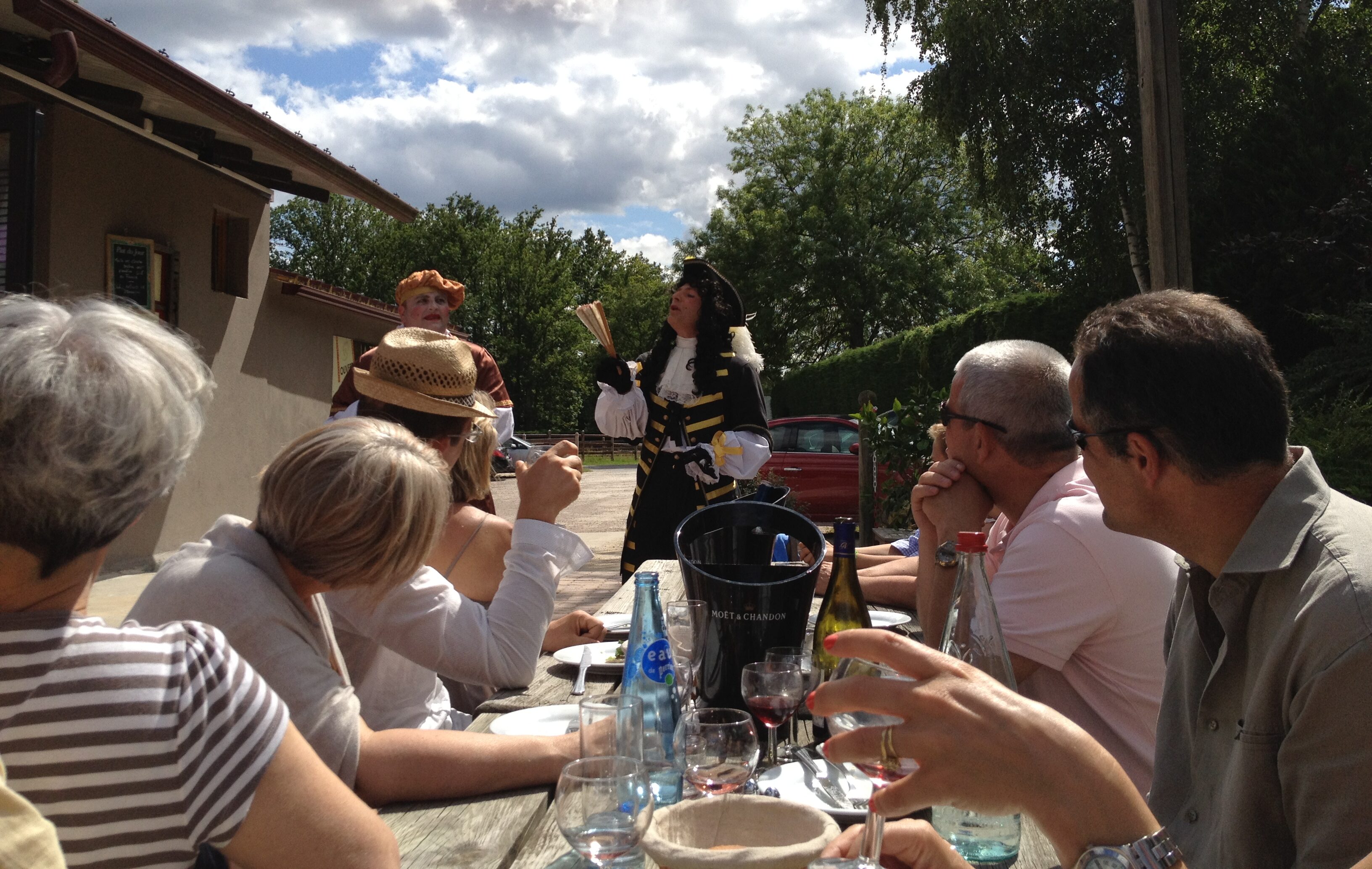 Deux comédiens jouant une pièce de théâtre devant un groupe de particuliers à table.