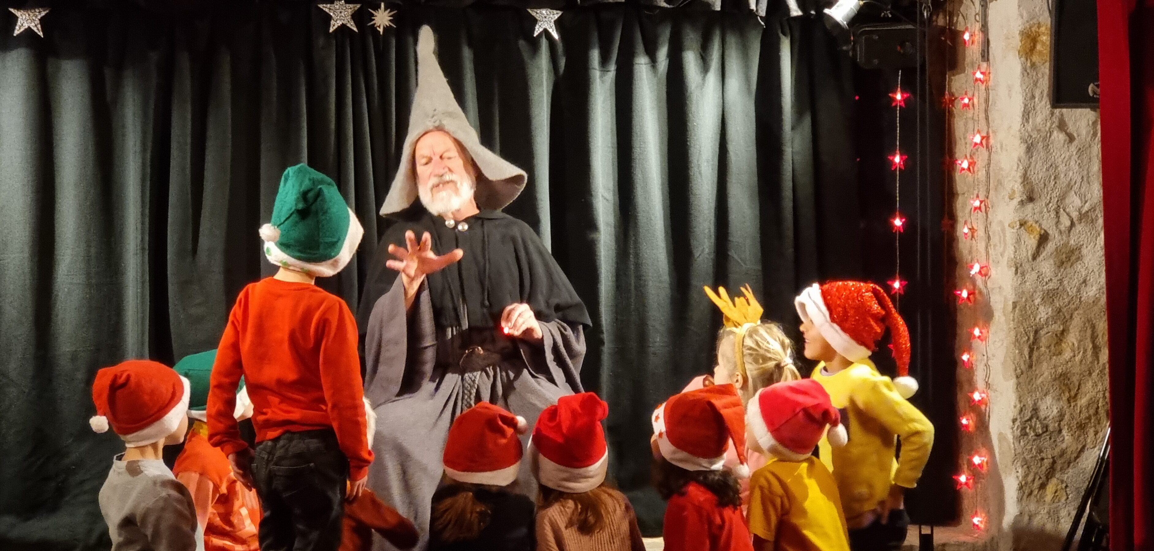Groupe d'enfants avec des chapeaux de Noël regardant un comédien.