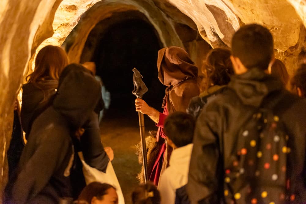Groupes de personnes de dos suivant un comédien dans une grotte.