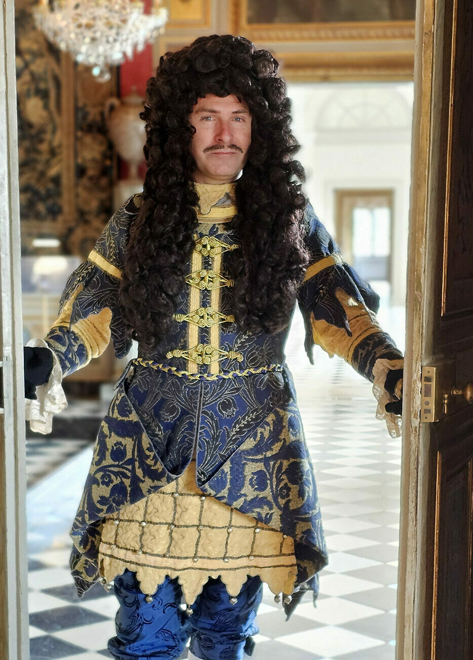 Un homme costumé ouvrant une porte.